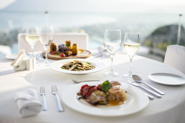 Una mesa dispuesta para una comida, con platos de comida, copas de vino y cubiertos.
