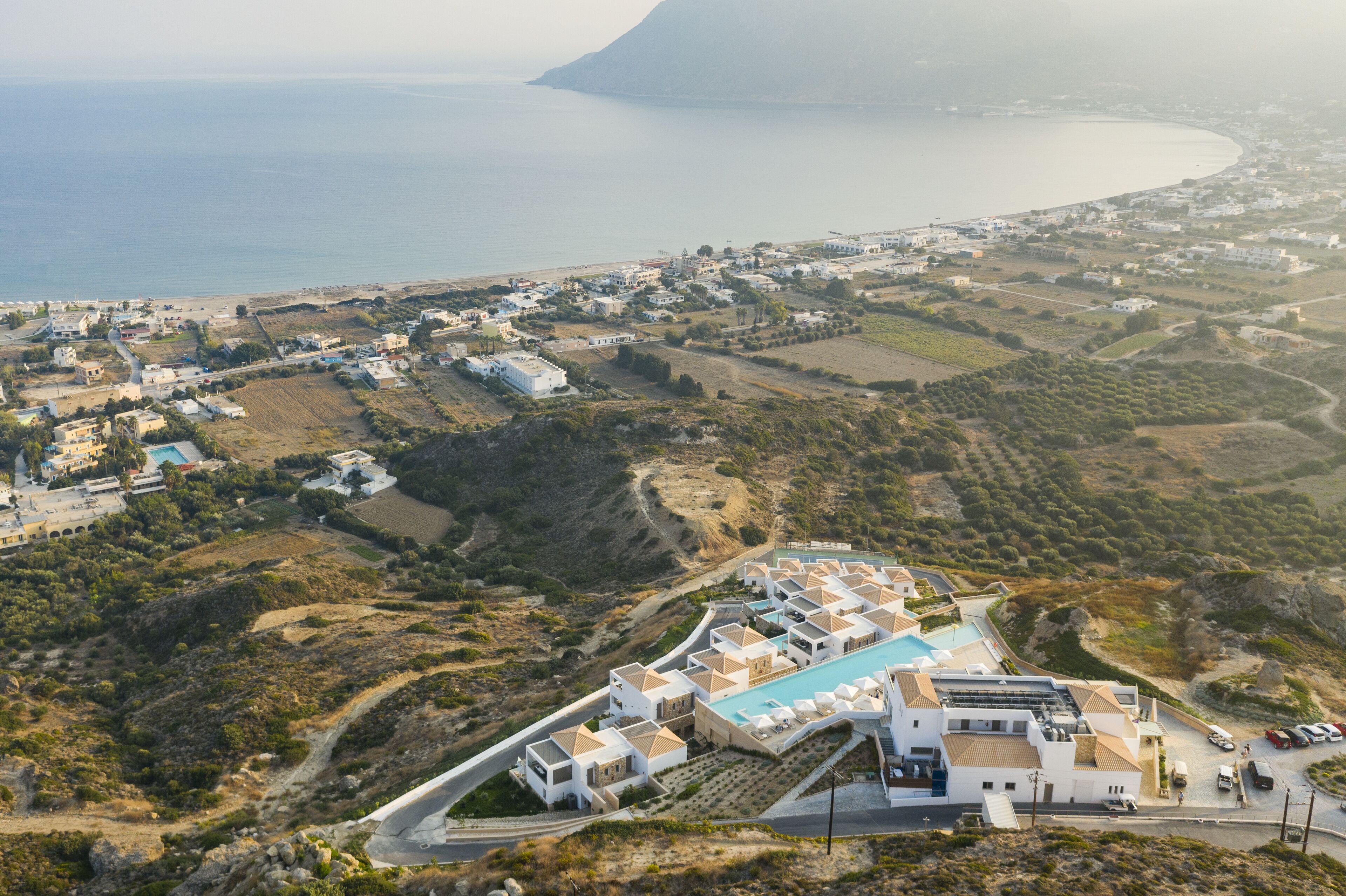 Une station balnéaire dotée d’une piscine, entourée de champs en terrasses et offrant une vue sur la mer.