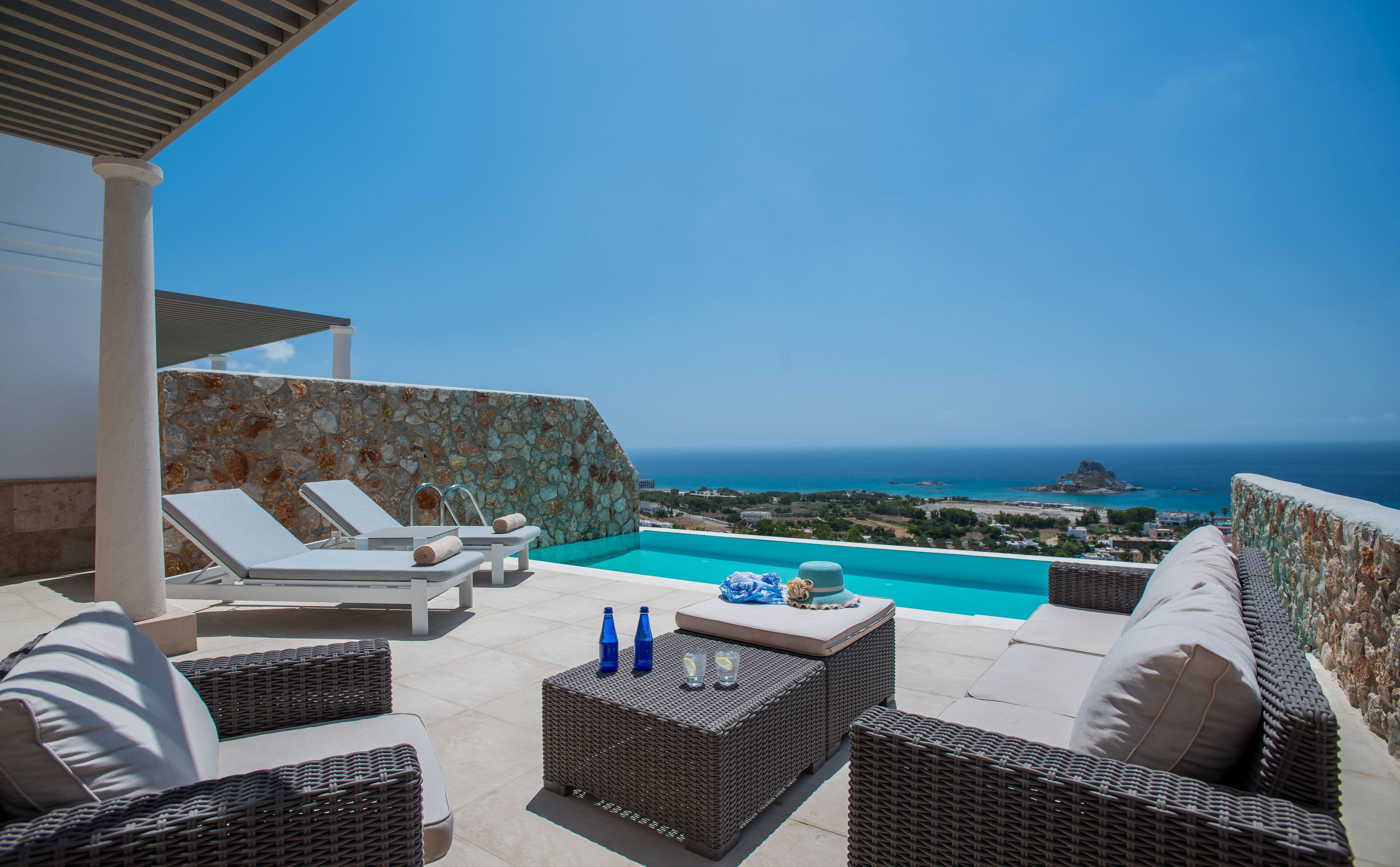 Eine Dachterrasse mit Pool, Liegestühlen und Korbmöbeln.