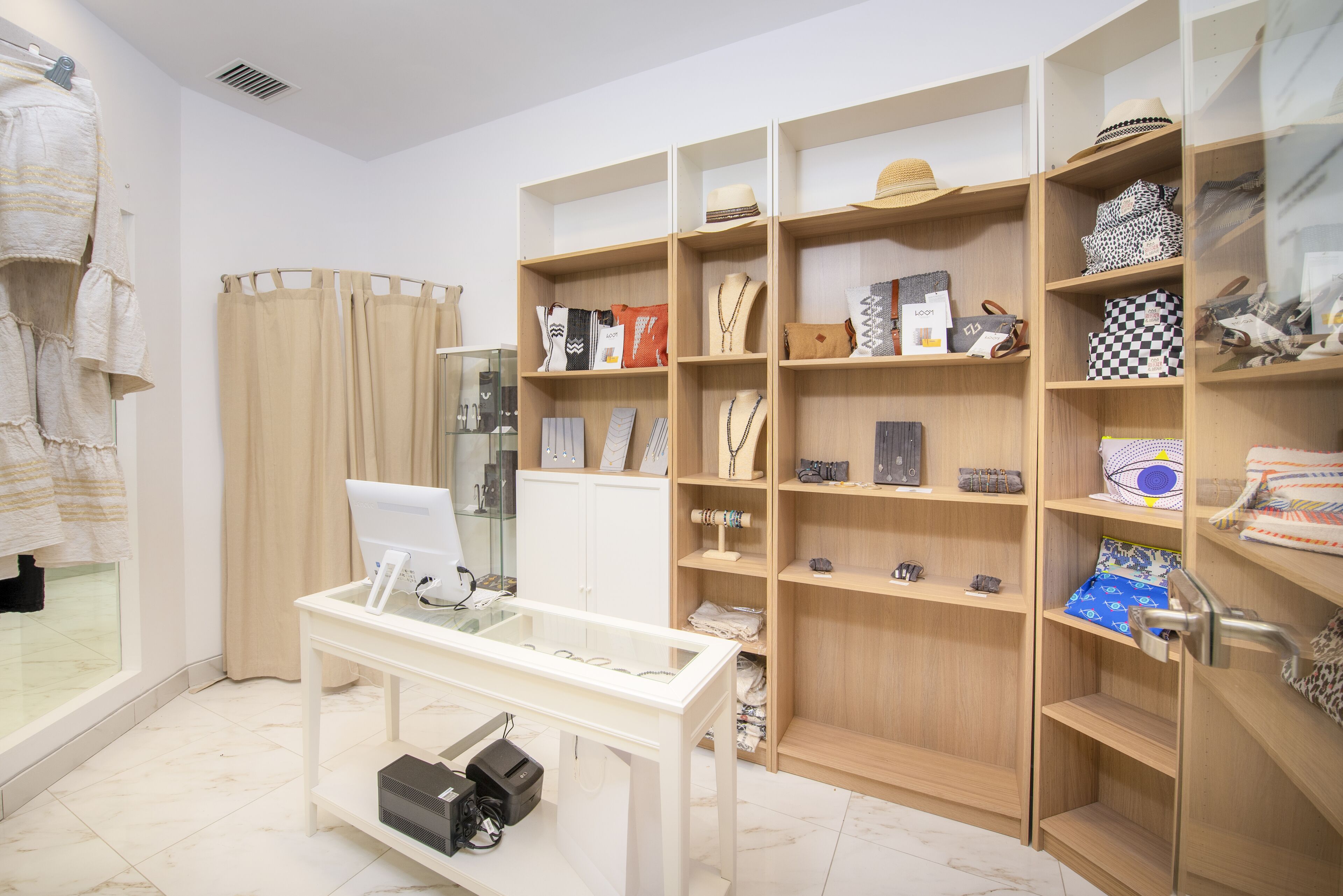 Una joyería con estantes llenos de accesorios, un mostrador con joyería y un maniquí.