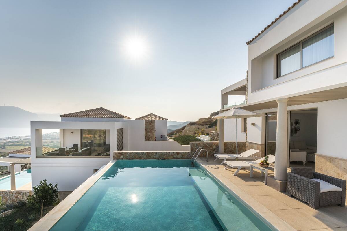 Un espace piscine moderne avec une eau d’un bleu cristallin, des chaises longues et une vue sur le paysage environnant.