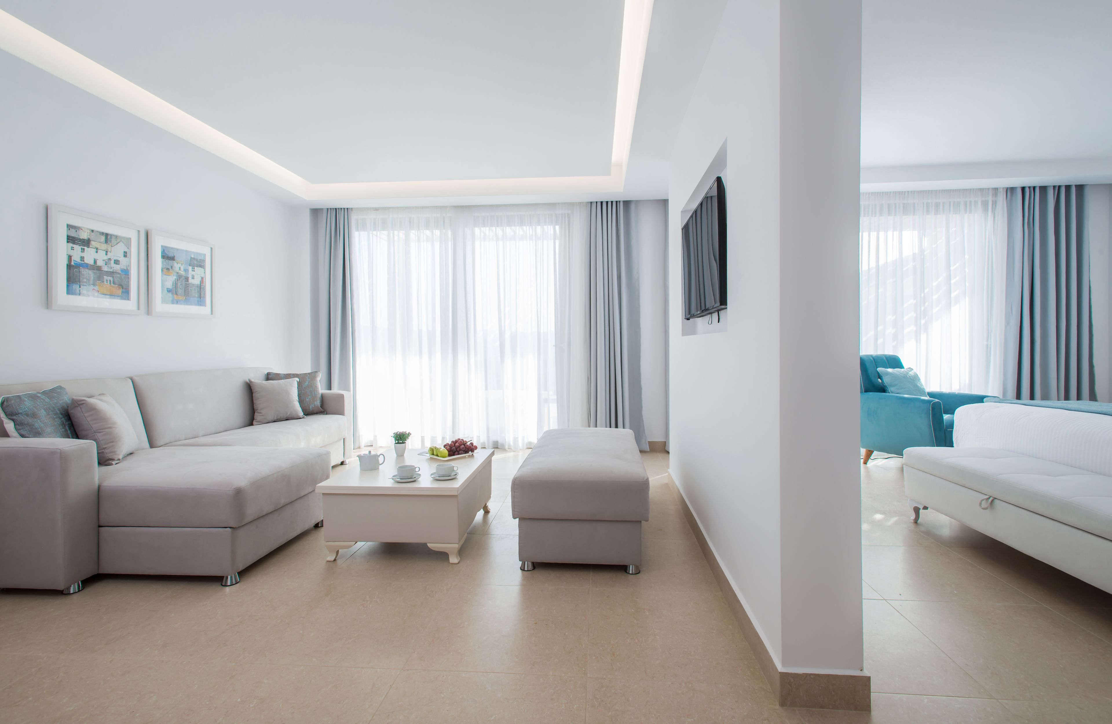 A modern hotel room with a sofa, a coffee table, a TV, and a bed.
