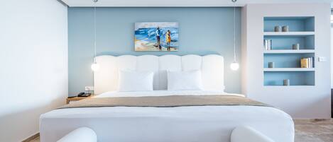 A modern bedroom with a white bed, a painting of a beach scene, and a built-in bookshelf.