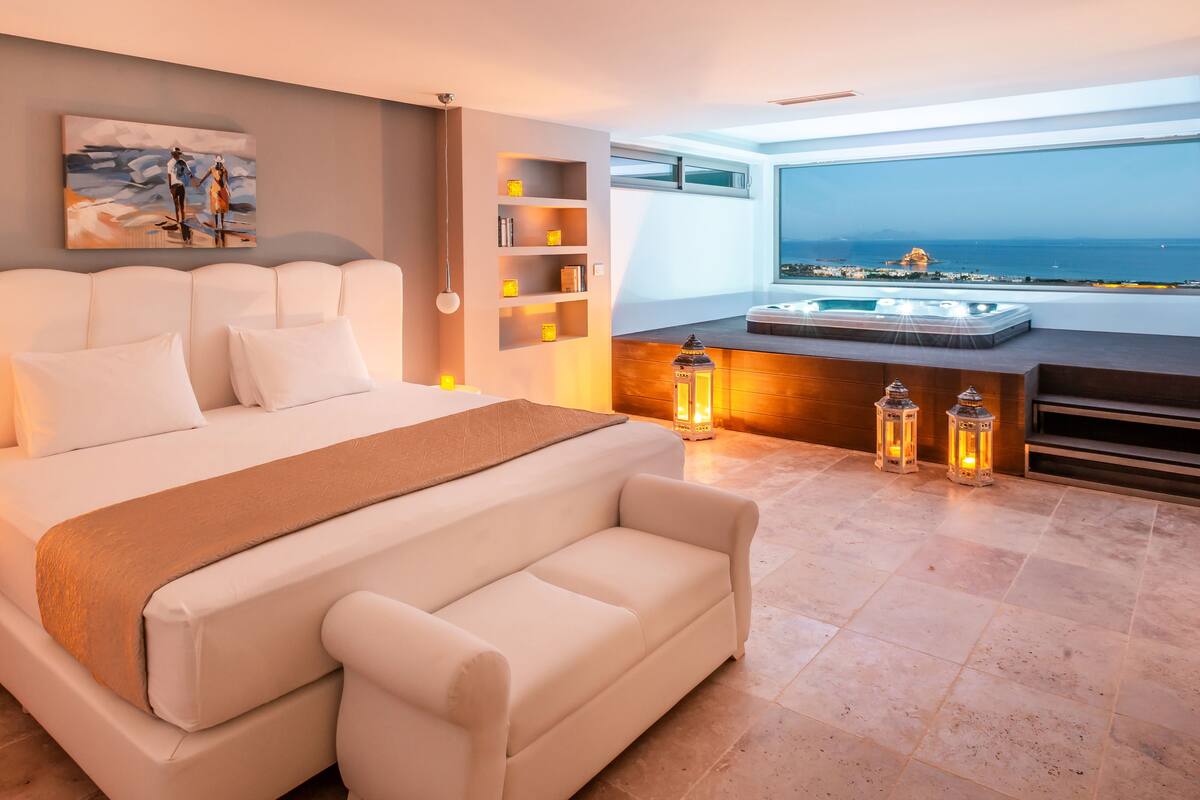 Une chambre moderne avec un grand lit, une vue sur la mer et un jacuzzi.