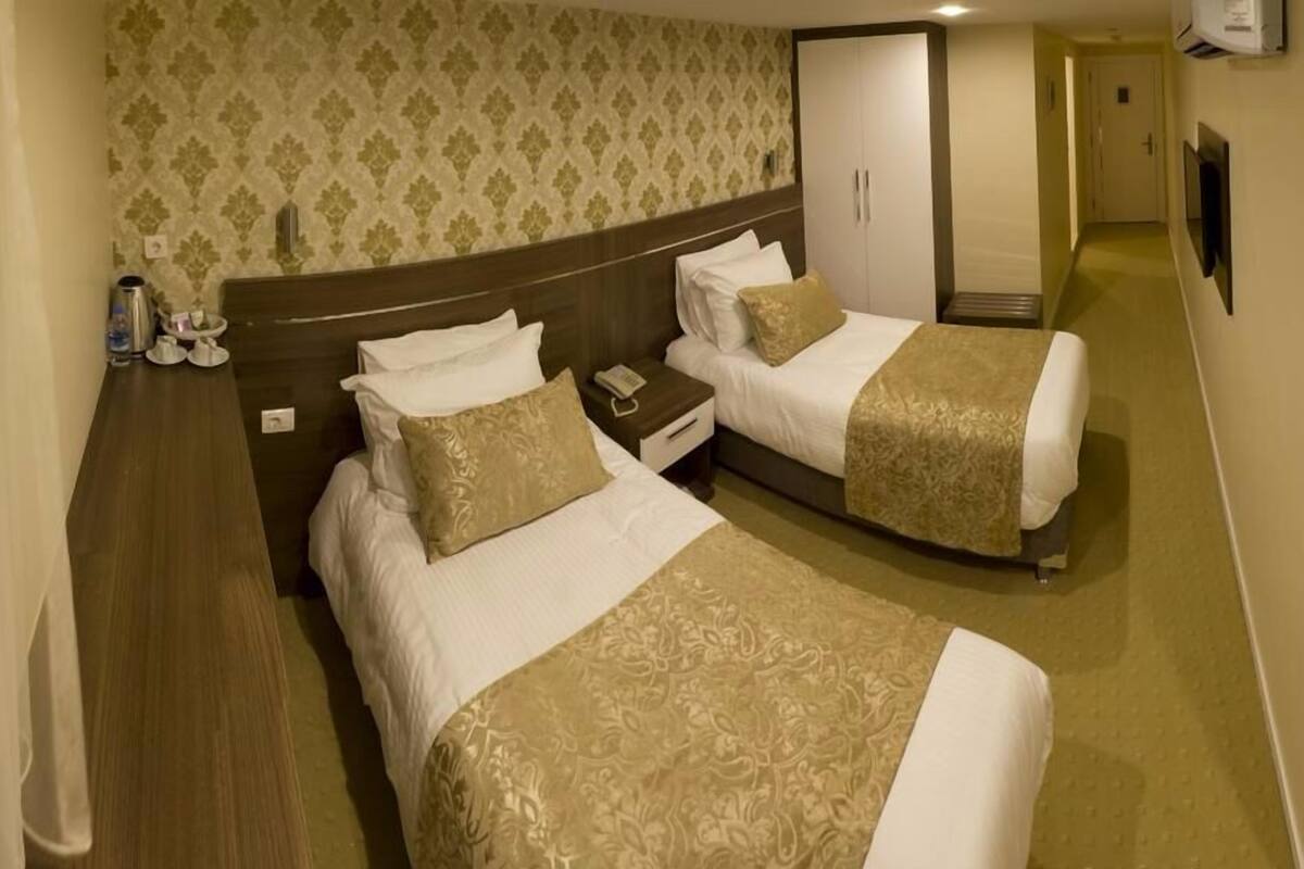 Een hotelkamer met twee bedden, een kledingkast, een nachtkastje en een spiegel.