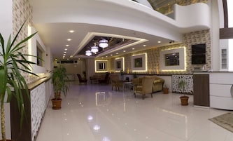 A spacious lobby with a high ceiling, recessed lighting, and a central seating area with sofas and tables.