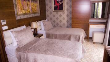 Une chambre d’hôtel avec deux lits, un bureau, une chaise et un miroir.