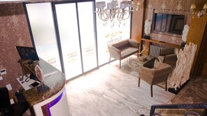 Un área de recepción con suelo de mármol, una mesa de recepción, una silla, un televisor y una pared decorativa con chimenea.