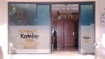 The entrance of the Kerimbey Hotel with a large glass facade, a chandelier, and a clock on the wall.