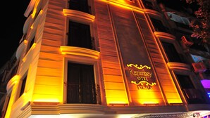 Fachada de hotel con señalización iluminada que dice 'Kempsey Hotel Kumila'.