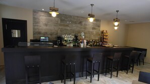 Una zona de bar moderna con una barra alargada, taburetes y una máquina de café.
