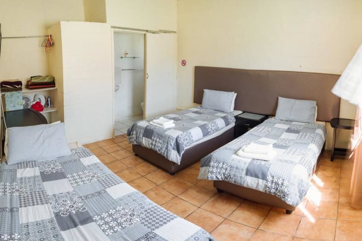 A room with two single beds, a small table, a chair, and a wardrobe.