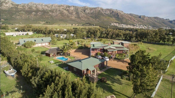 A residential area with multiple houses, a swimming pool, and a mountainous backdrop. - Kingfisher Hollow Exclusive Guest House (Cape Town)