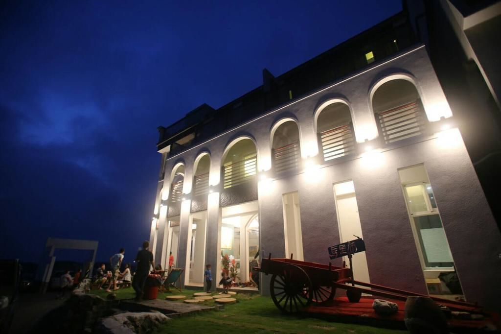 Un edificio con ventanas arqueadas y un carruaje rojo estacionado al frente.