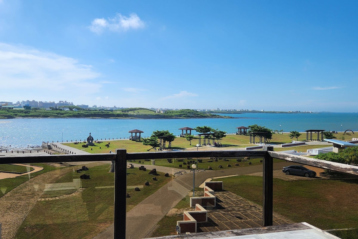 Un parque costero con senderos, pabellones y vistas al mar.