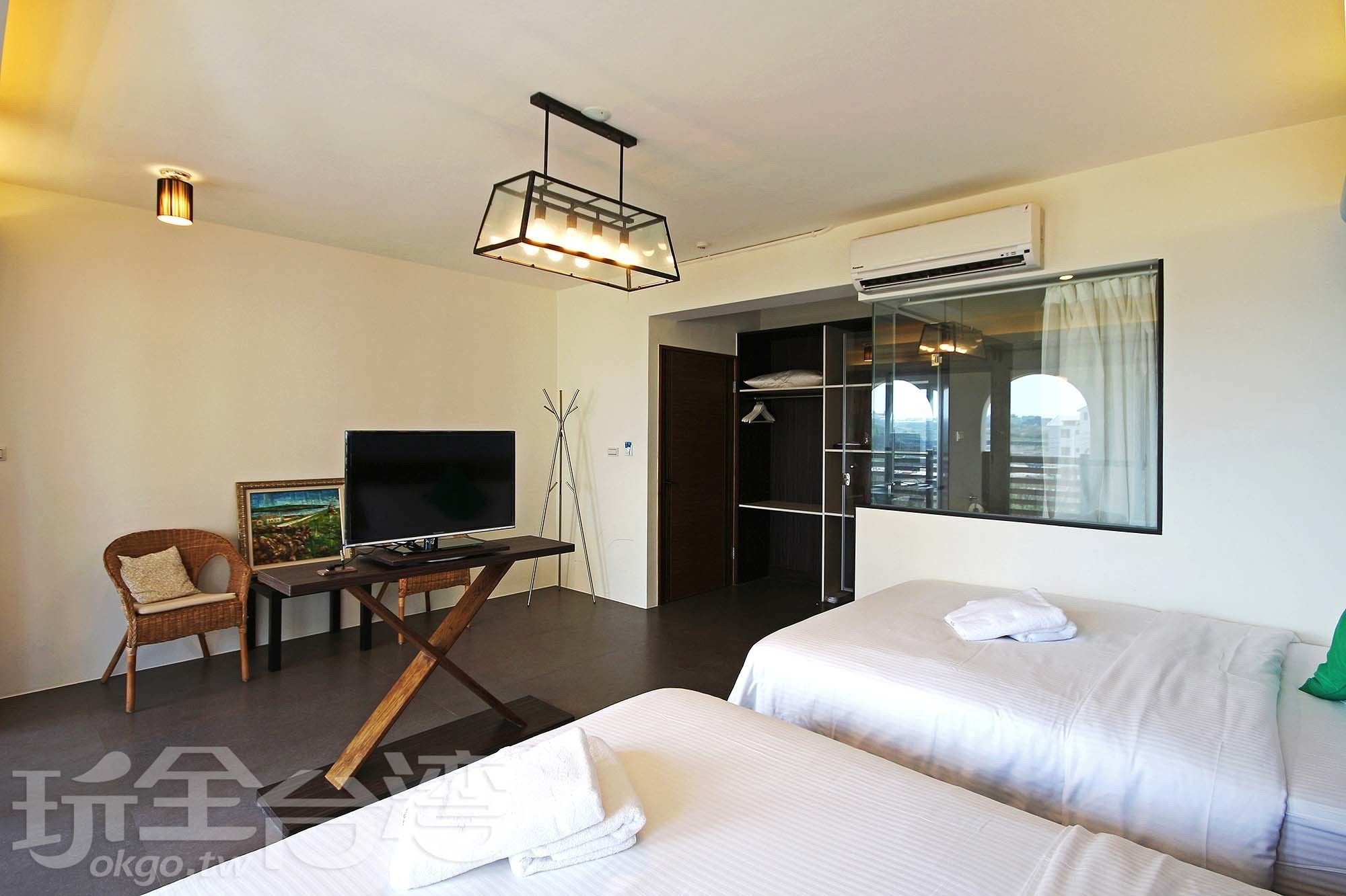 A hotel room with two beds, a TV, a desk, and a wardrobe.