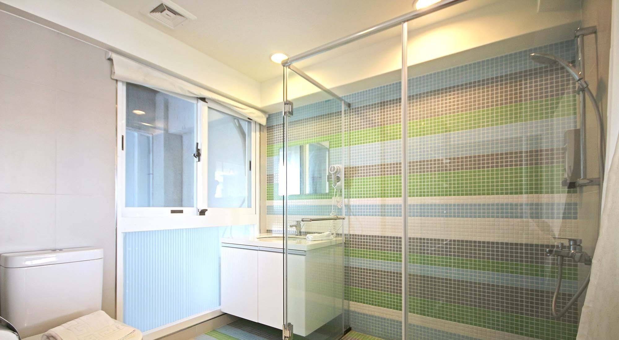 A modern bathroom with a glass shower enclosure, a toilet, and a sink with a mirror.