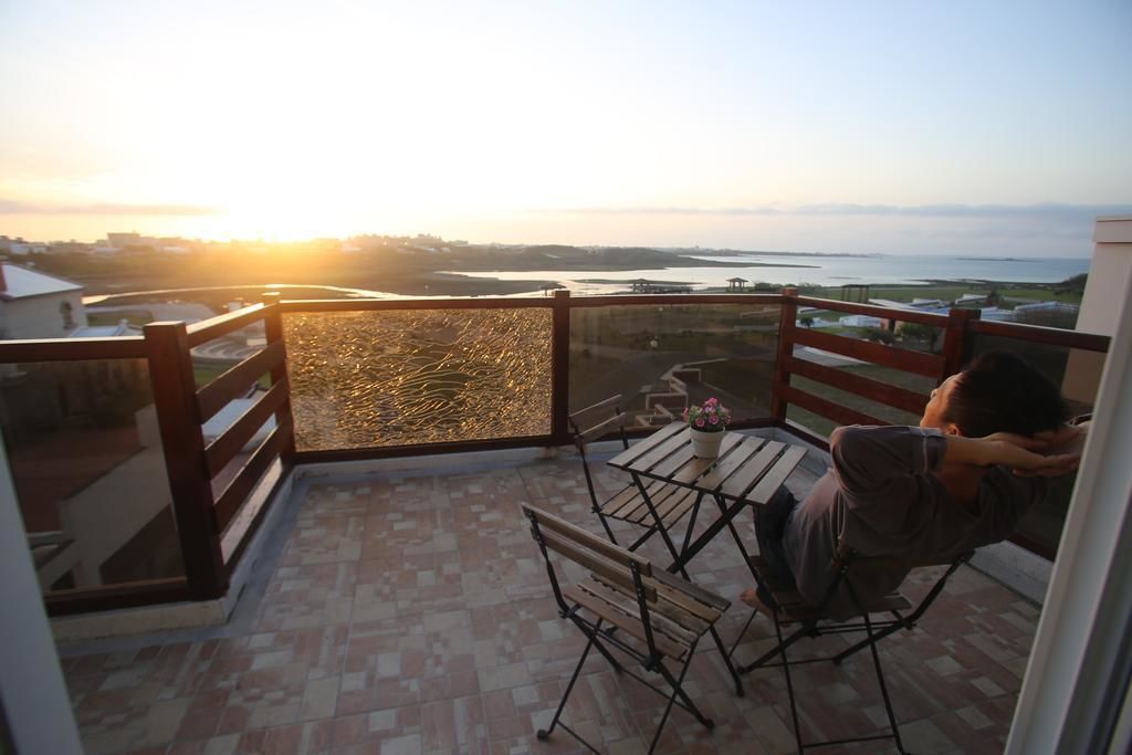 A balcony with a view of a body of water during sunset.