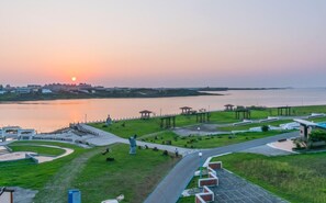 Ein Park mit Wegen, Lauben und Blick auf den Sonnenuntergang über dem Wasser.