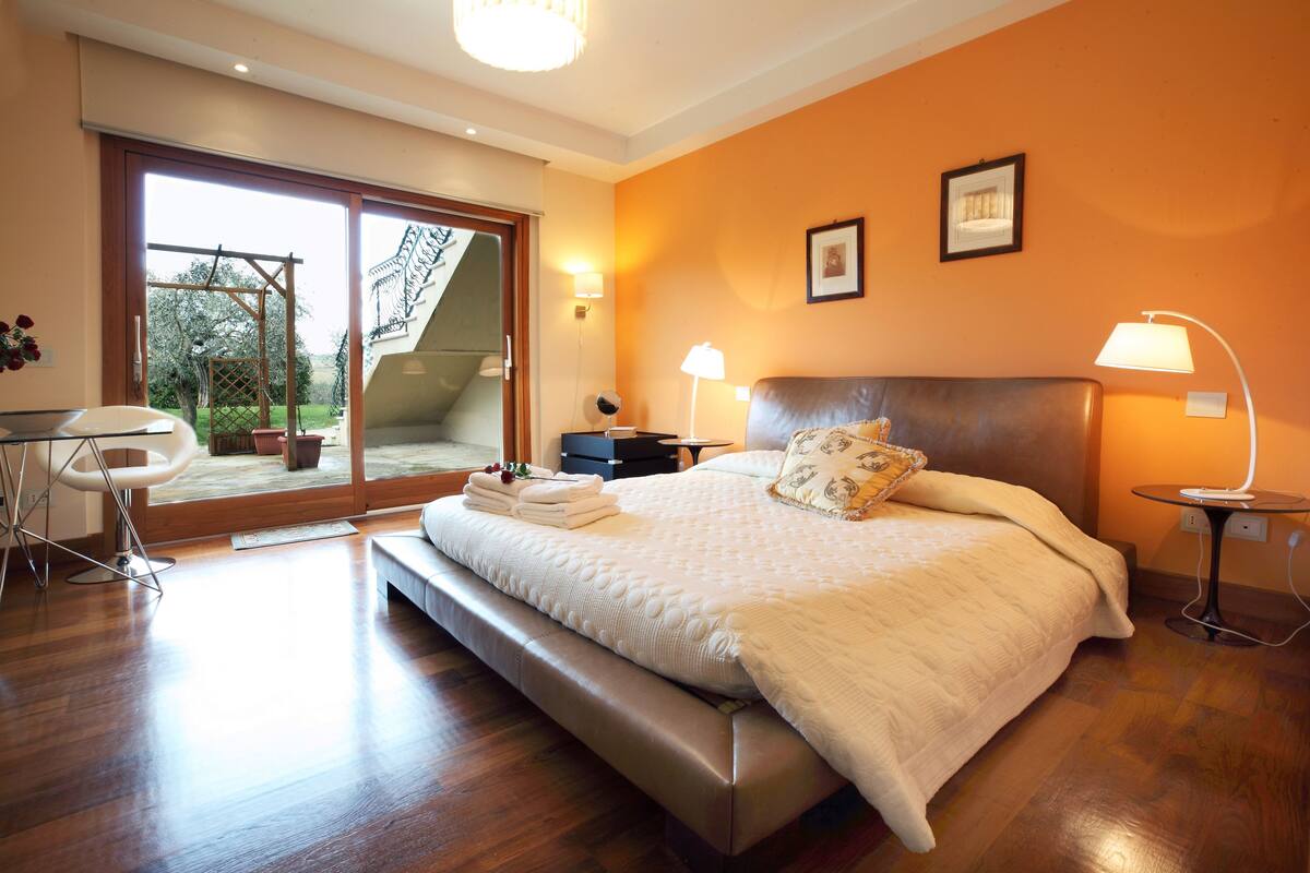 Une chambre avec un grand lit, un bureau et une chaise. Un escalier mène à un balcon.