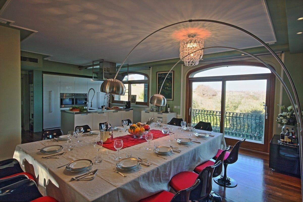 Un coin repas avec une table dressée pour six personnes, un lustre et une vue sur l’extérieur.