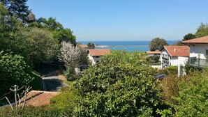 Un pueblo costero con casas tradicionales, vista despejada al mar y abundante vegetación.
