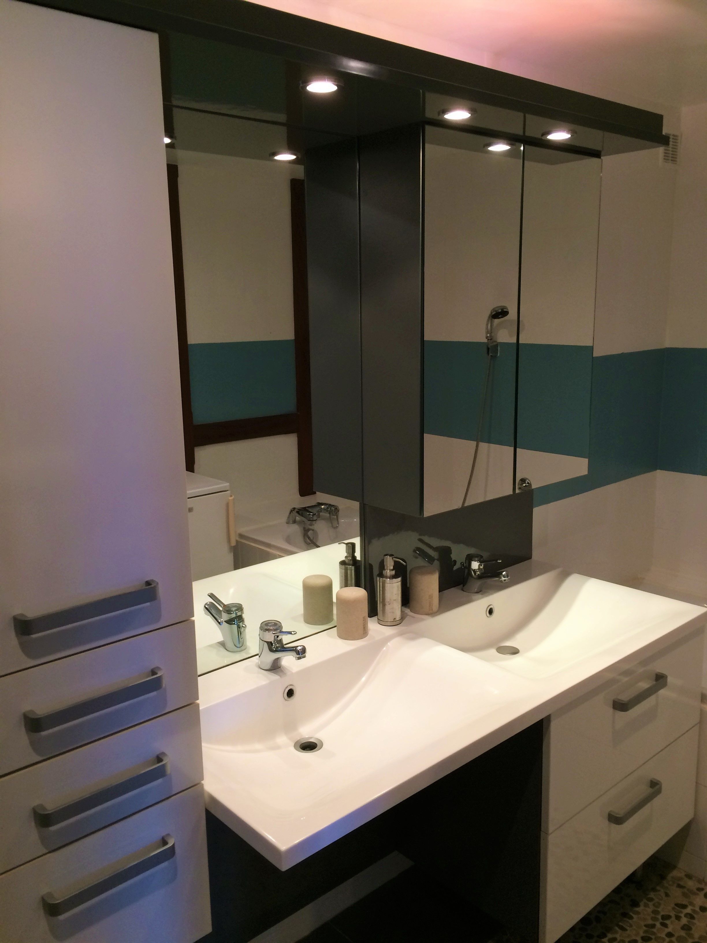 A modern bathroom with a white vanity, a large mirror, and a shower area.