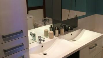 A modern bathroom with a white vanity, a large mirror, and a shower area.