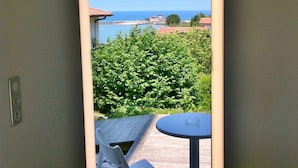 Un balcón con vista al mar, una mesa y una silla.