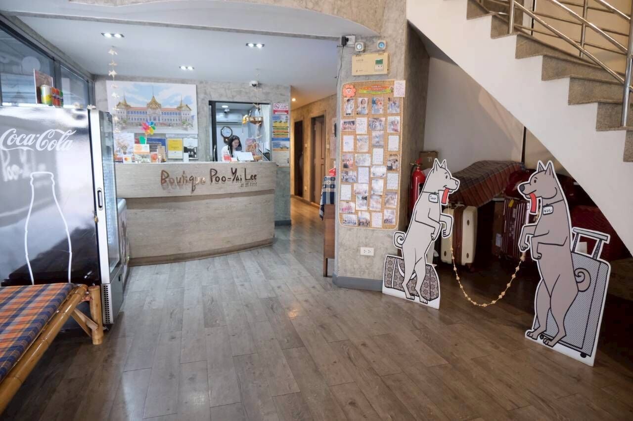 Un vestíbulo de hotel con un mostrador de recepción, un refrigerador de Coca-Cola, una barra de madera con un letrero y un tablón de anuncios con recortes de perros.