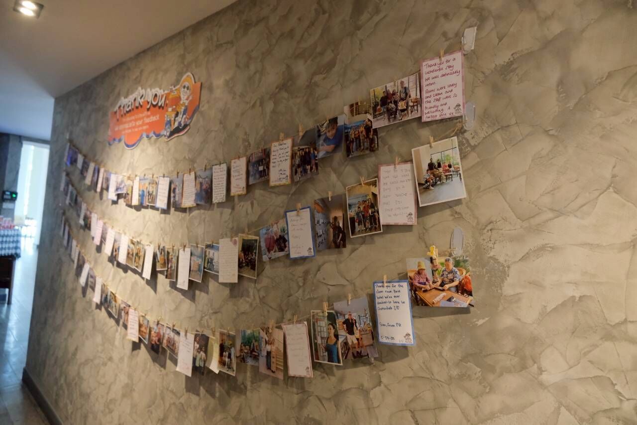 A wall with a series of photographs and notes, including a prominent 'Thank you' sign.