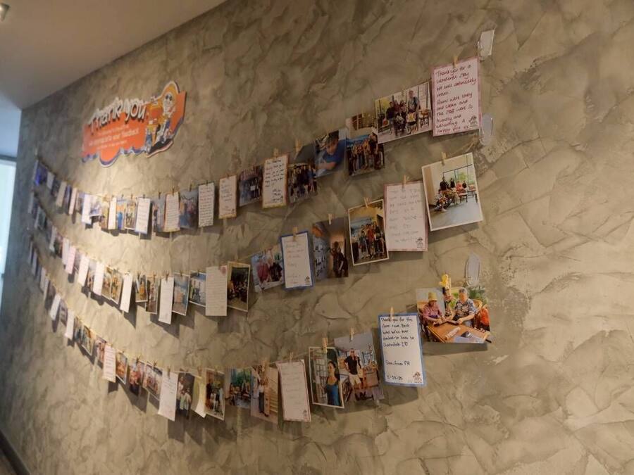 A wall with a series of photographs and notes, including a prominent 'Thank you' sign.