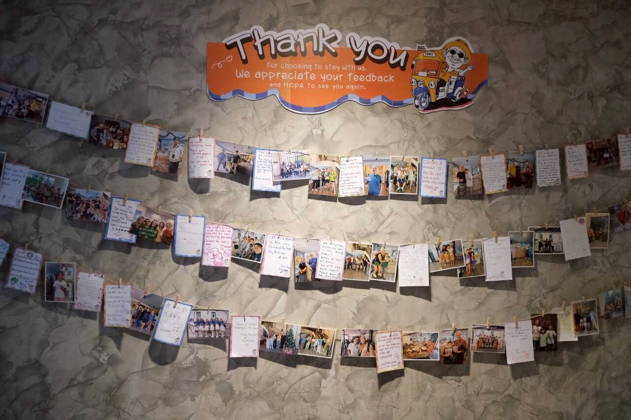 A wall with a 'Thank you' sign and various photos and notes pinned to it.