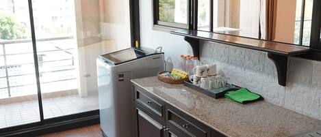 A kitchen with a built-in oven, a microwave, and a coffee maker. There is a window with a view of buildings outside.