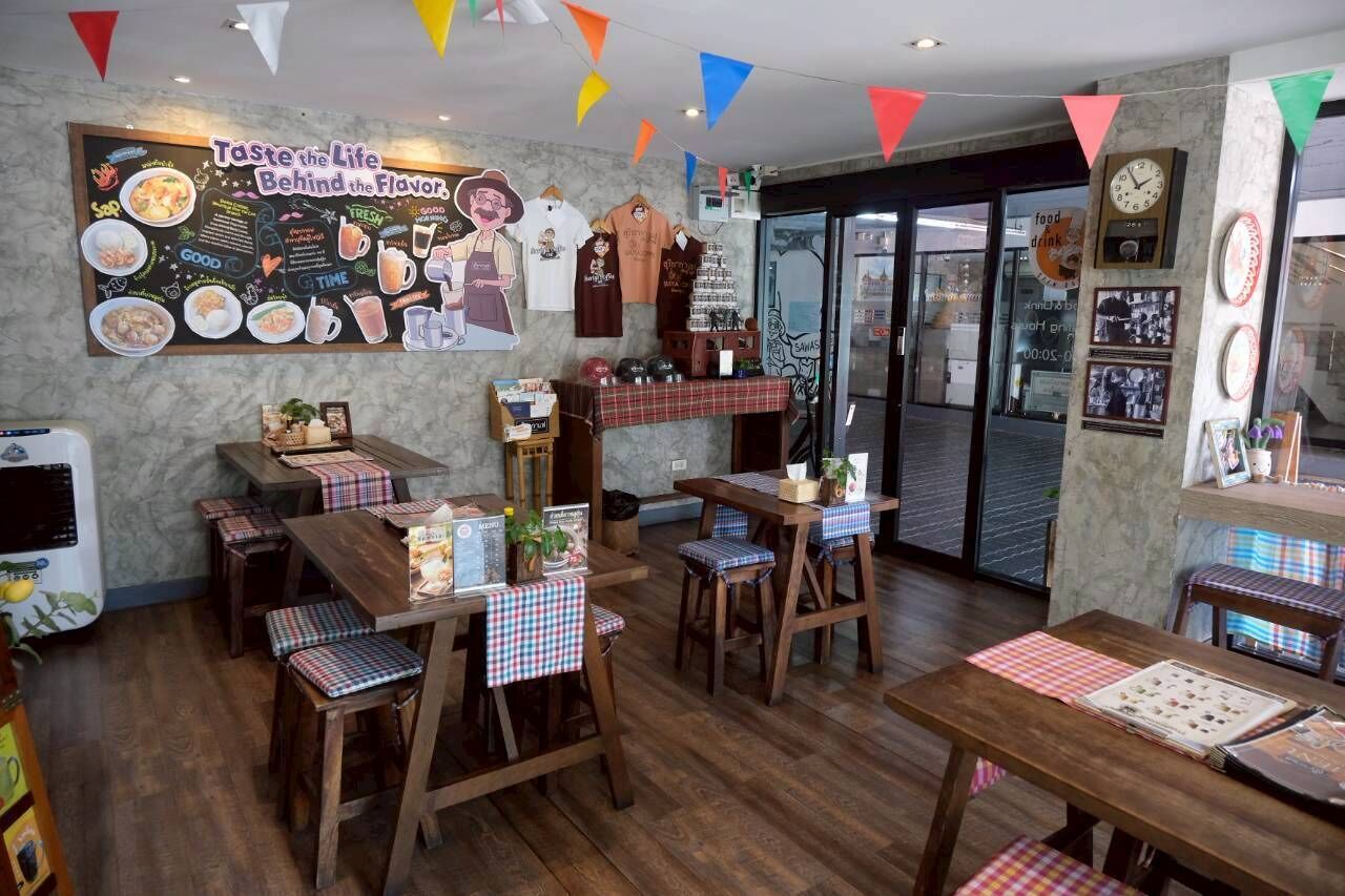 A restaurant interior with wooden tables and chairs, a chalkboard menu, and colorful triangular flags.