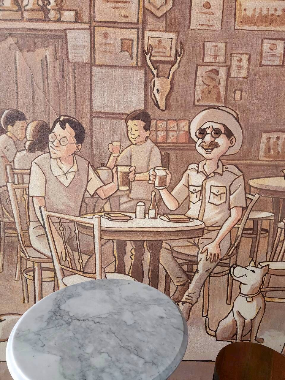A mural of a bar scene with patrons and a dog.