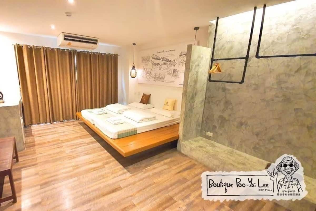 Un dormitorio con cama, escritorio, televisor y aire acondicionado instalado en la pared.