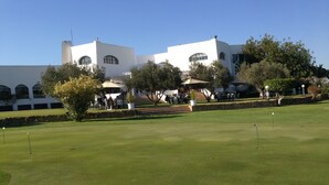 Un parcours de golf doté d’un club-house comprenant un espace extérieur avec des sièges et un escalier menant à l’entrée.