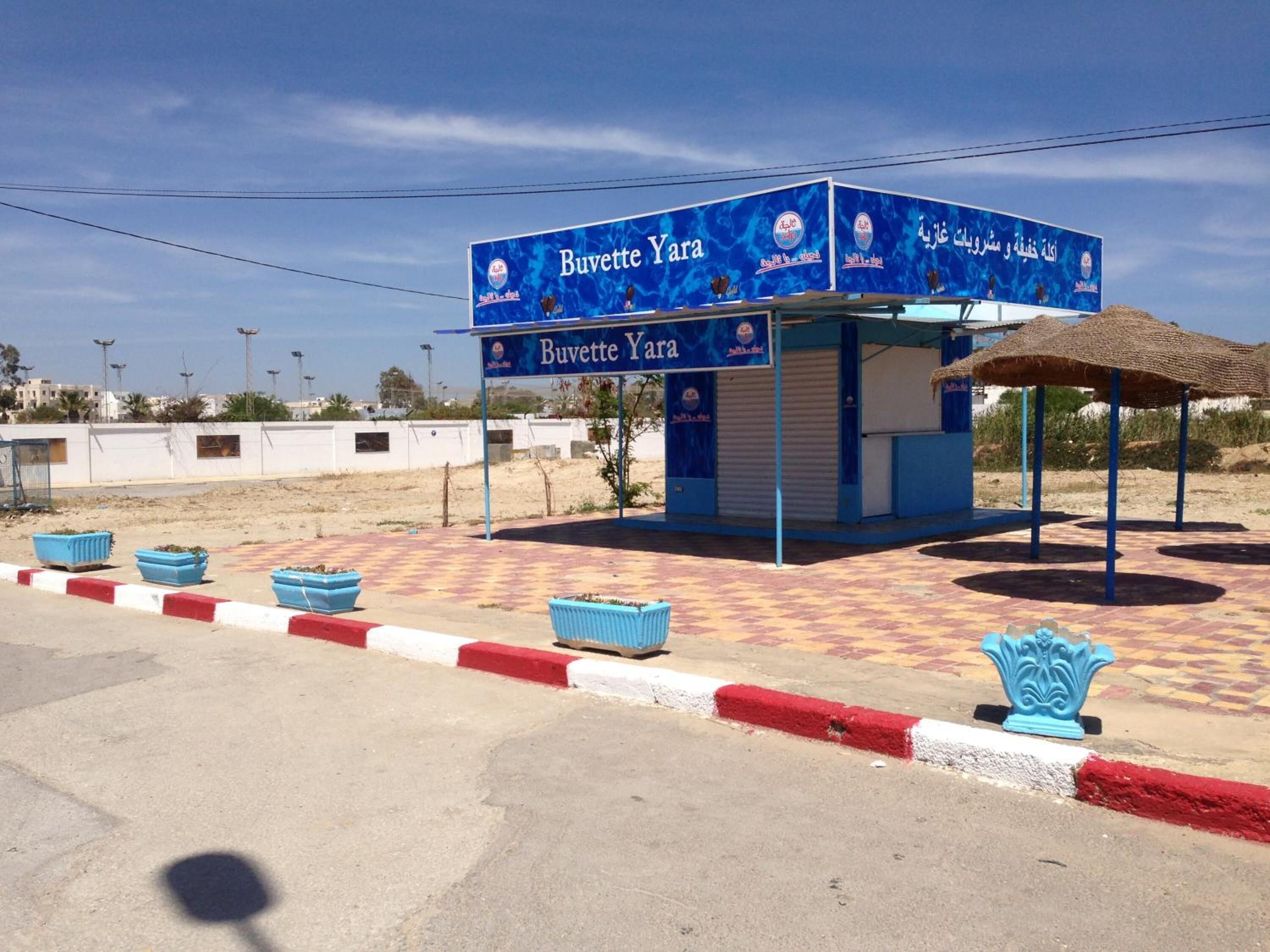 A small, single-story building with a blue and white color scheme, featuring a sign that reads "Buvette Yara."