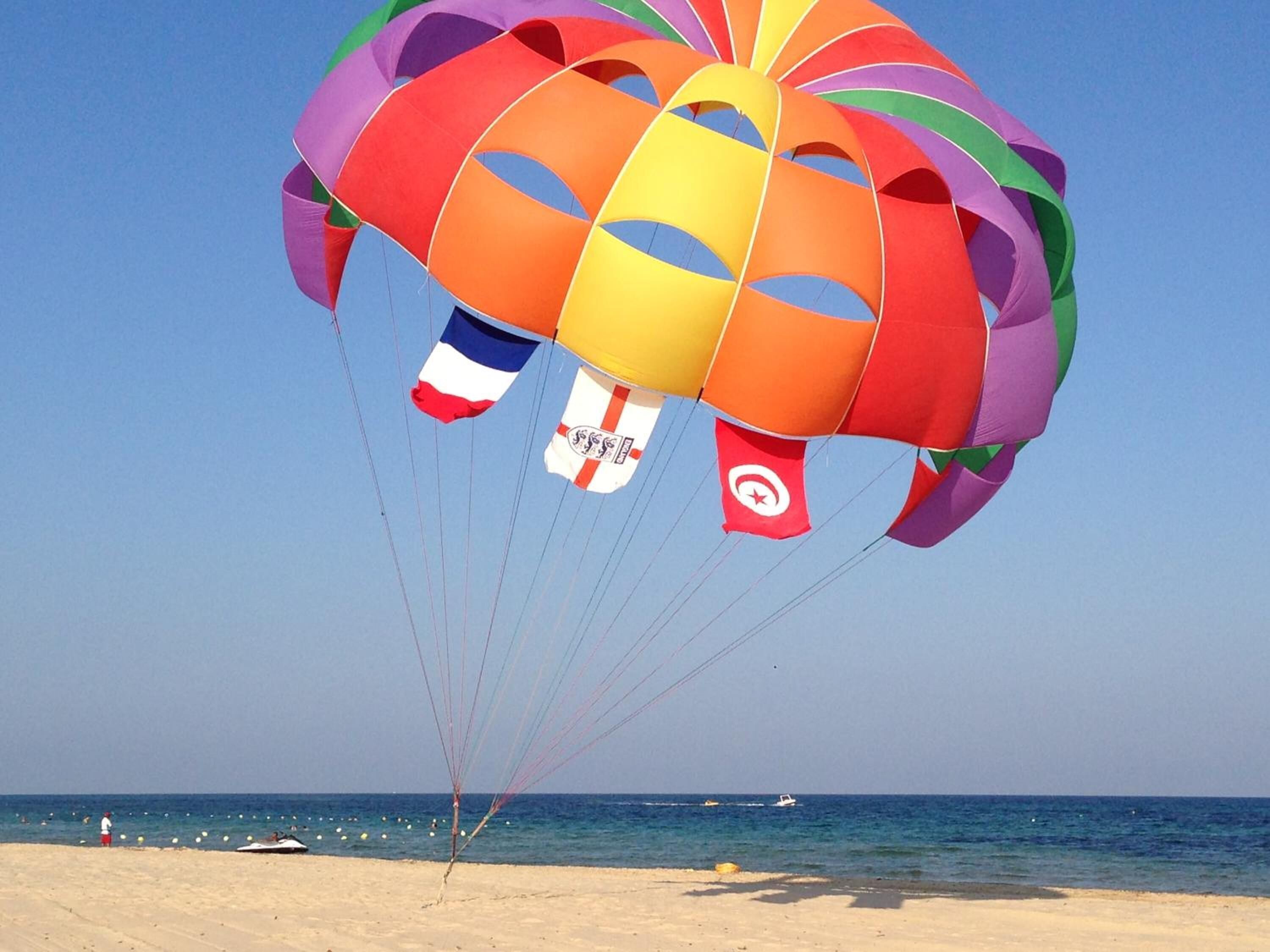 Un paraschermo colorato con bandiere sopra una spiaggia.