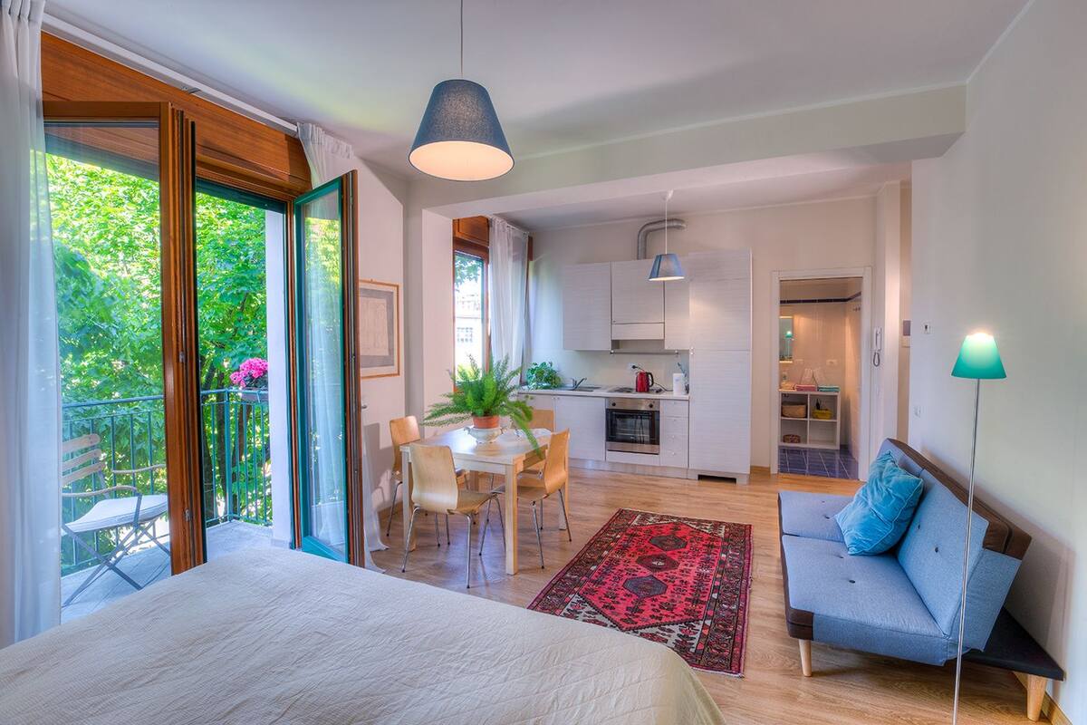 A modern apartment with a balcony, a dining area, a kitchen, and a living room.