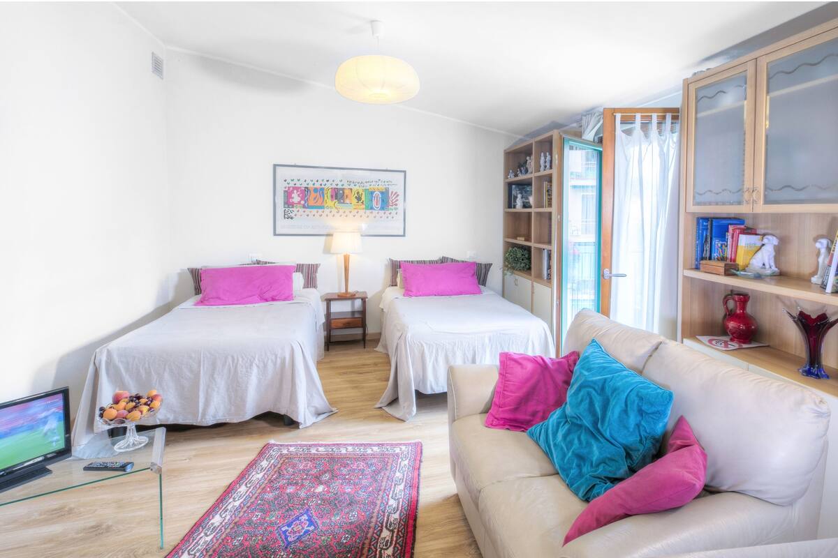 A room with two beds, a sofa, a TV, and a bookshelf.