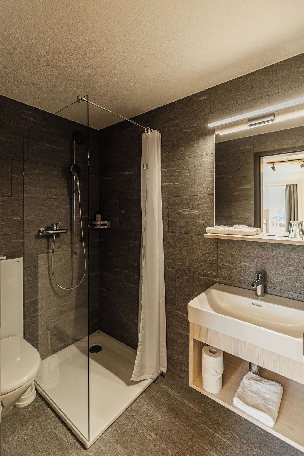A modern bathroom with a glass-enclosed shower, a white sink, and a mirror above it.