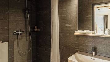 A modern bathroom with a glass-enclosed shower, a white sink, and a mirror above it.