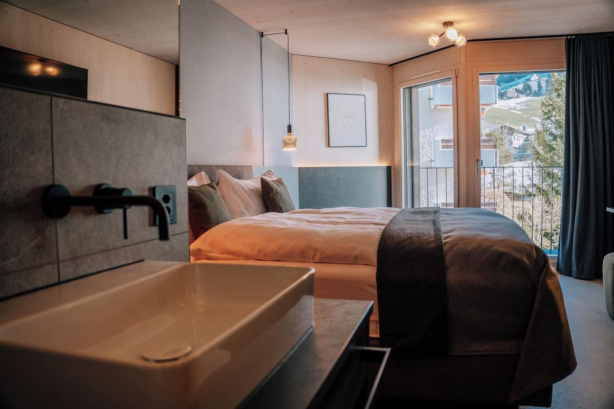 Ein modernes Schlafzimmer mit einem großen Bett, einer Badewanne und einem Balkon mit Blick.