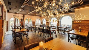 Ein Restaurant mit Holztischen und -stühlen, einem Kronleuchter und großen Fenstern.
