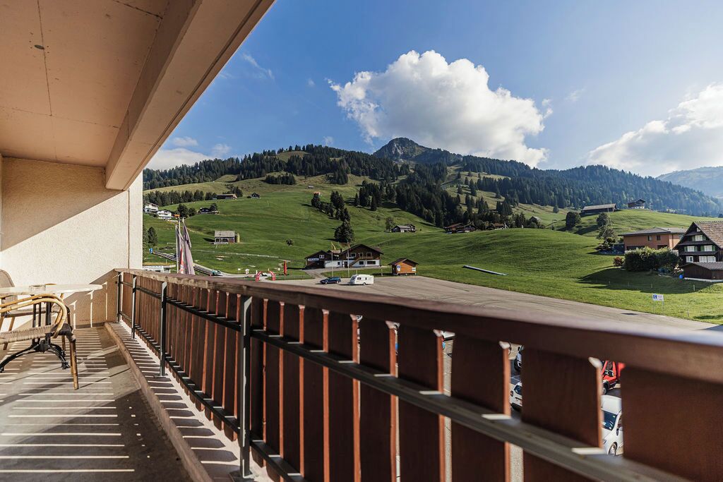 Ein Balkon mit Blick auf ein grünes Tal und Berge.