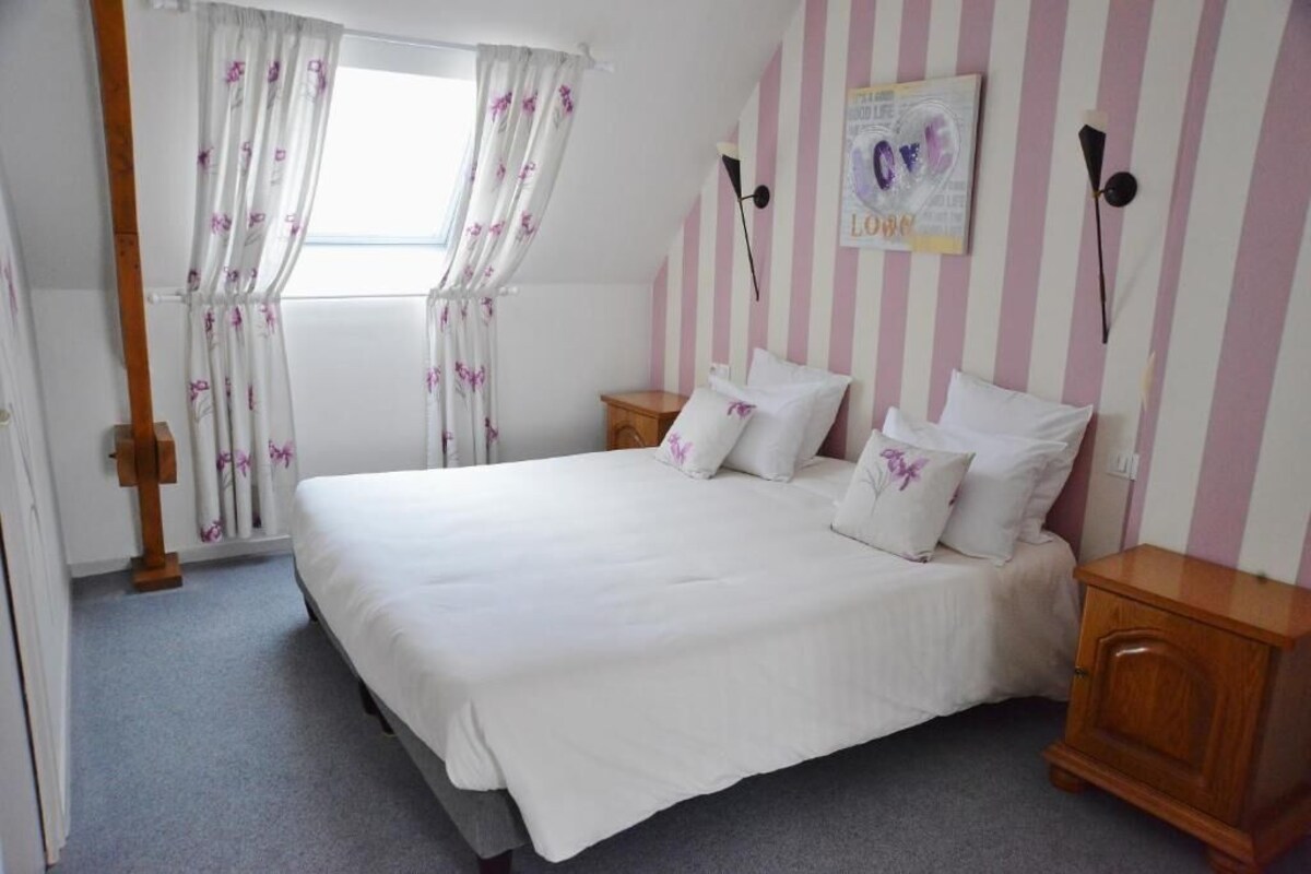 A bedroom with a bed, curtains, a wall clock, and a poster.
