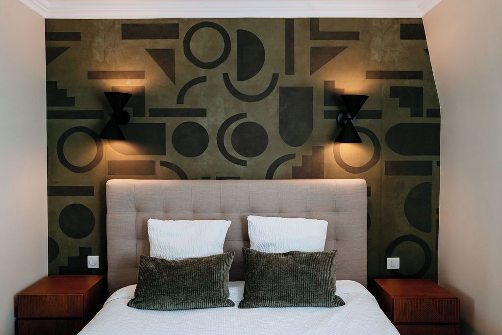 Ein Schlafzimmer mit einem großen Bett, zwei Nachttischen und einer Wand mit geometrischem Muster.