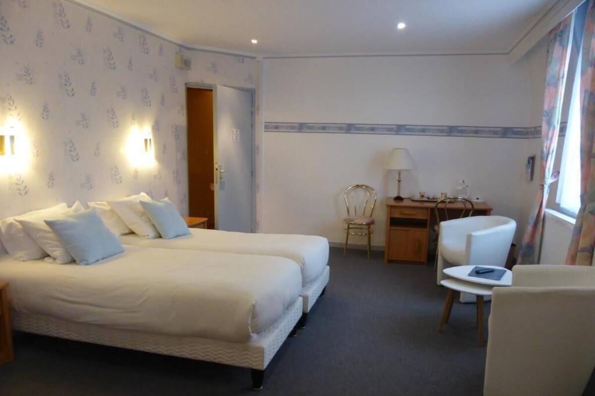 A hotel room with a double bed, a desk, a chair, and a lamp.